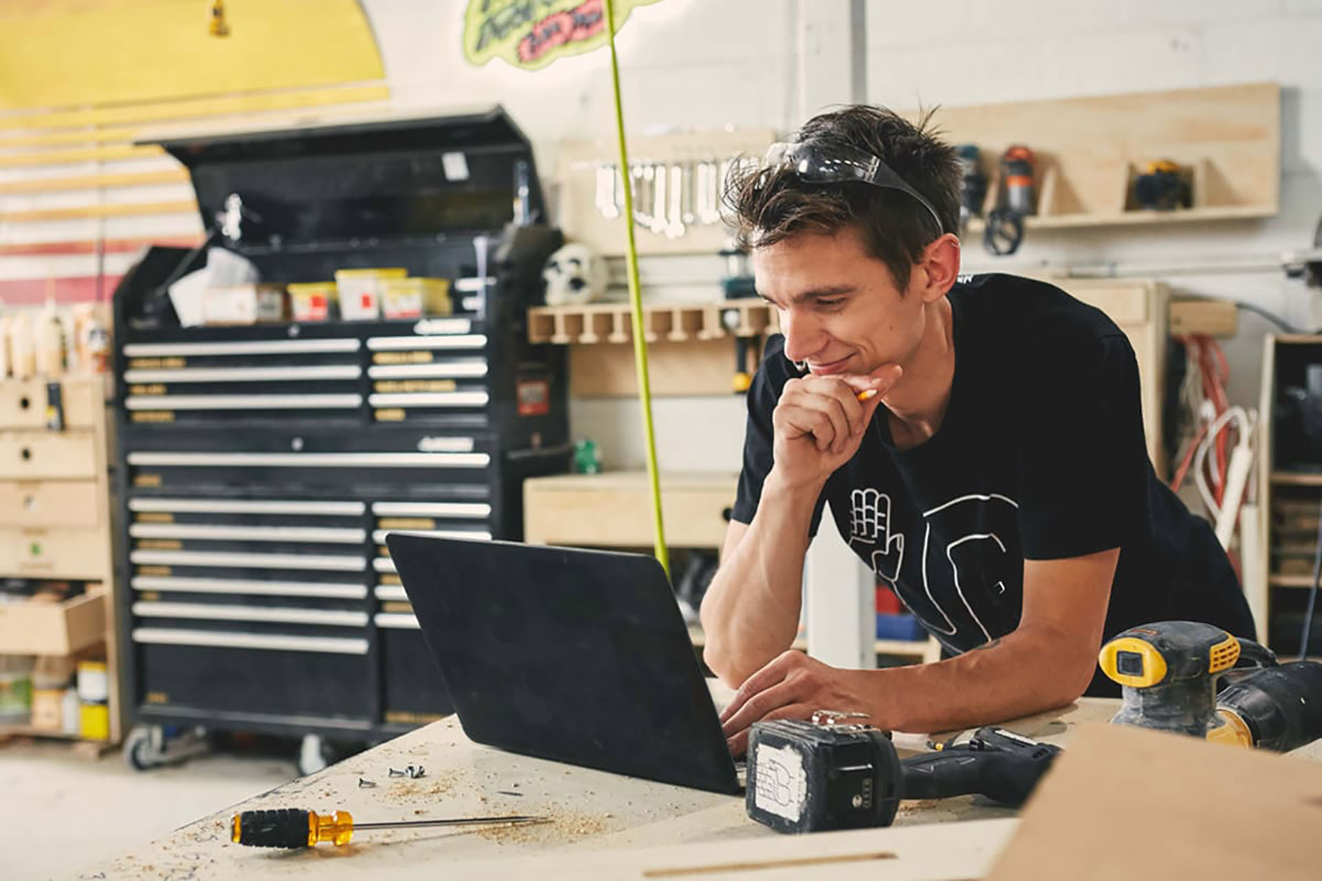 Man smiling at laptop in a workshop setting